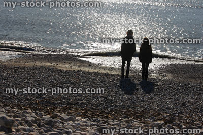 Stock image of boy and girl on beach, silhouettes against sea