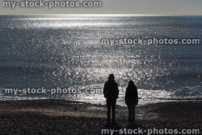 Stock image of children silhouettes on beach facing into sunshine / sea