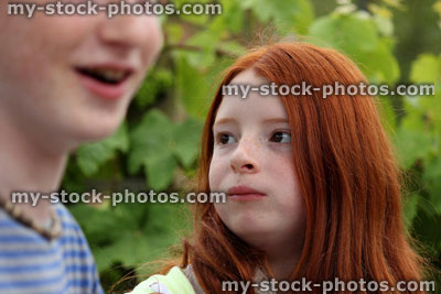 Stock image of brother and sister eating at garden party / barbecue