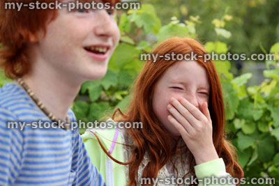 Stock image of brother and sister laughing at joke in garden
