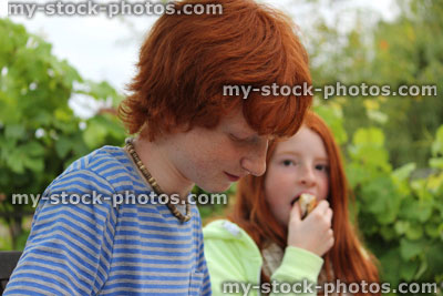 Stock image of brother and sister eating at garden party / barbecue