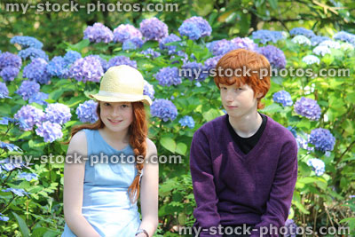 Stock image of boy and girl sitting on bench in garden