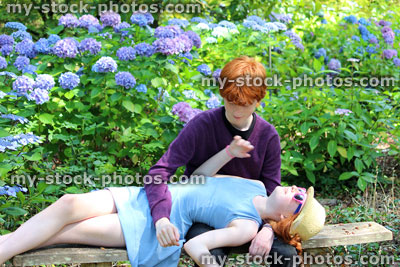 Stock image of boy and girl messing about on garden bench, sitting, lying down