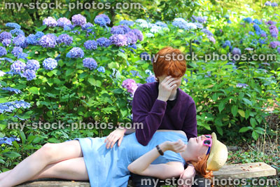 Stock image of boy and girl messing about on garden bench, sitting, lying down
