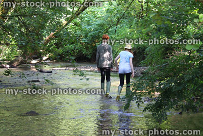 Stock image of boy and girl playing / paddling / wading in river, woodland