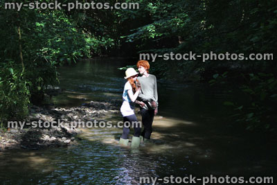 Stock image of boy and girl playing / paddling / wading river, woodland