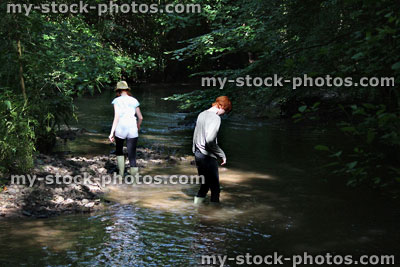 Stock image of boy and girl playing / paddling / wading in river, woodland