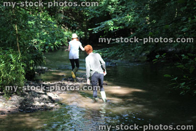 Stock image of boy and girl playing / wading in river, woodland walk