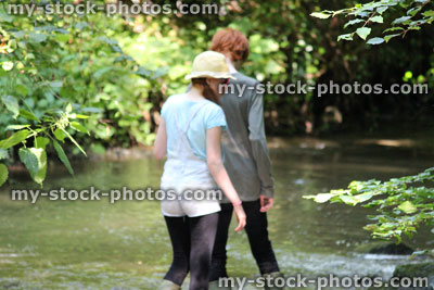 Stock image of boy and girl playing / wading in river, woodland walk