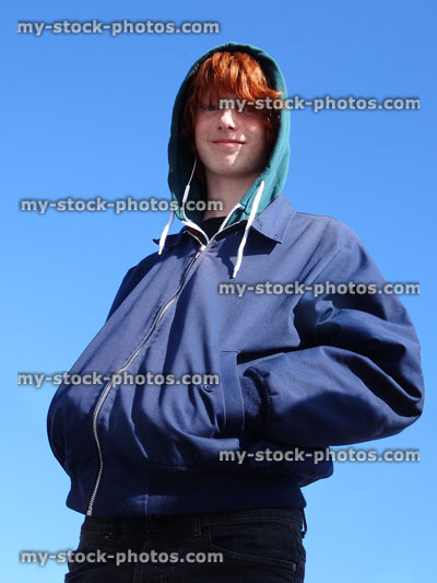 Stock image of teenage boy with hoodie / red hair, isolated against blue sky