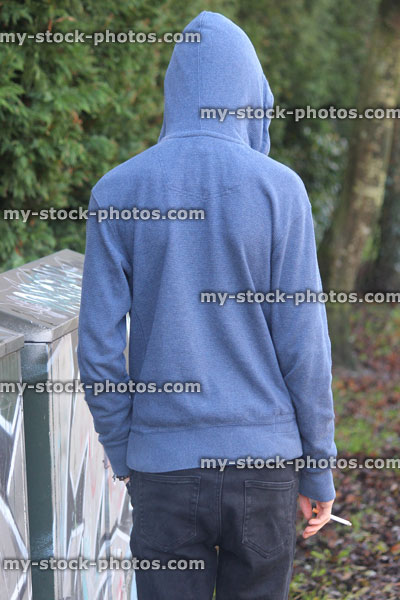 Stock image of teenage boy smoking underage / youth wearing hoodie / hood, graffiti, pathway