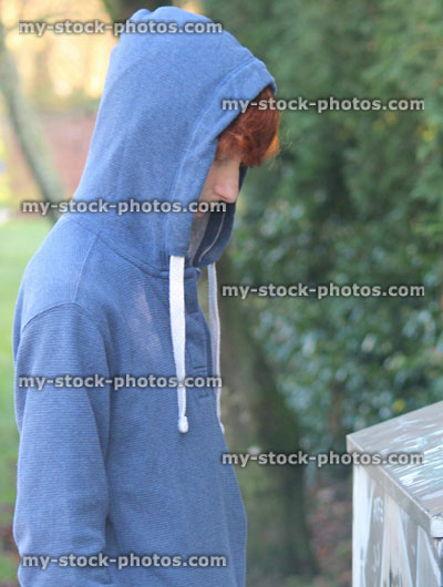 Stock image of troubled teenage boy / youth wearing hoodie / hood, graffiti