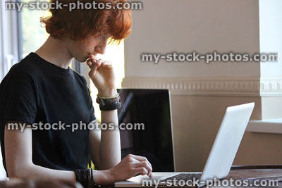 Stock image of teenage boy doing homework on laptop computer