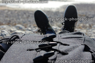 Stock image of man sunbathing in the winter, wearing duffle coat