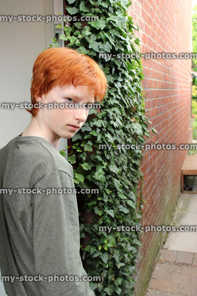 Stock image of teenage boy looking moody, walking through door, red hair