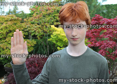 Stock image of teenage boy hoding up hand to say 'stop'