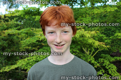 Stock image of happy teenage boy in garden, short red hair, smiling