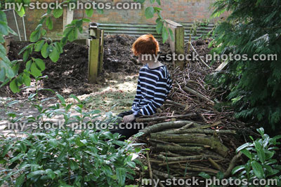 Stock image of teenage gardener boy taking rest in garden, sitting by compost heaps