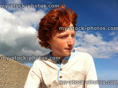 Stock image of red headed boy sat on seawall