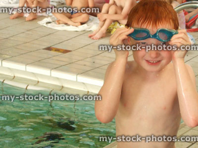 Stock image of young boy taking off swimming goggles, copy space 