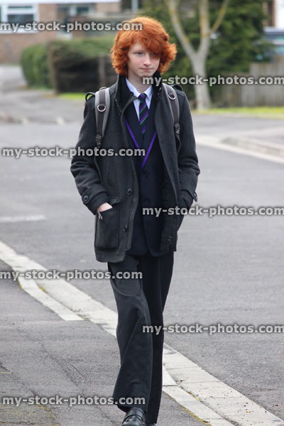 Stock image of school-boy walking home along road wearing uniform / tie