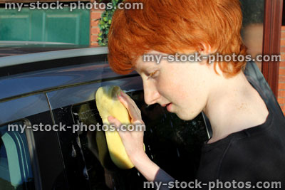 Stock image of teenage boy washing car window with sponge / car wash