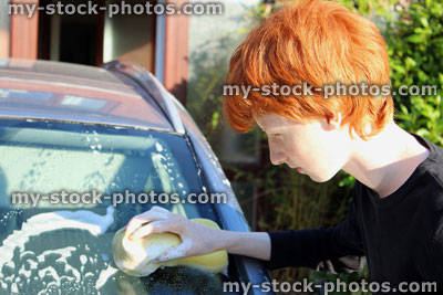 Stock image of teenage boy washing car windscreen with sponge / car wash