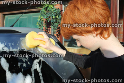 Stock image of teenage boy washing car window with sponge / car wash