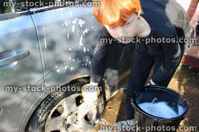 Stock image of teenage boy washing car wheel with sponge / car wash