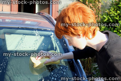 Stock image of teenage boy washing car windscreen with sponge / car wash