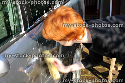 Stock image of teenage boy washing car door with sponge / car wash