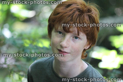 Stock image of teenage boy standing in wood / woodland / forest, red hair