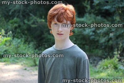 Stock image of teenage boy standing in wood / woodland / forest, red hair
