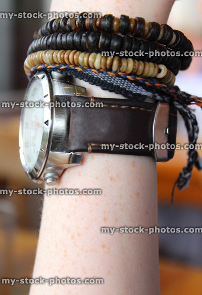 Stock image of teenage boy's wrist, with leather bracelets, friendship bracelets, watch