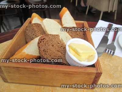 Stock image of freshly baked homemade sliced bread in basket / wooden box with butter