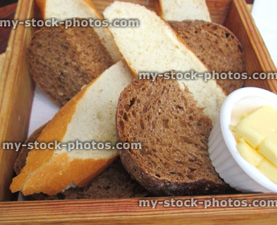 Stock image of freshly baked homemade sliced bread in basket / wooden box with butter
