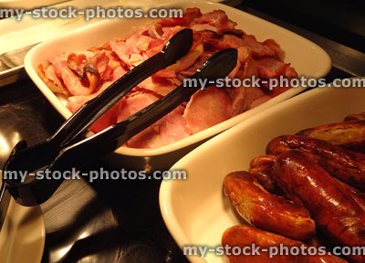 Stock image of fried breakfast buffet under heat lamps, sausages and bacon