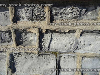 Stock image of cement mortar pointing between limestone blocks, brick wall