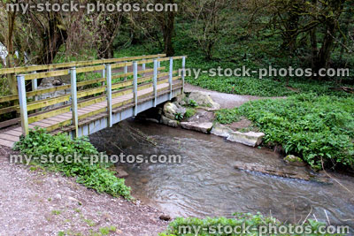 Stock image of foot bridge in countryside, crossing fast flowing stream