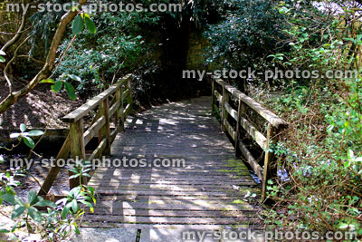 Stock image of small wooden bridge across stream in landscaped gardens
