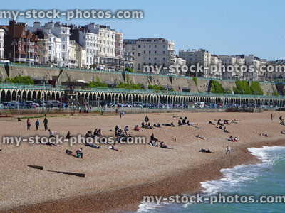 Stock image of busy beach in Brighton with sunbathers / seafront promenade