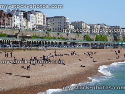Stock image of sunbathers on Brighton beach in spring, background hotels