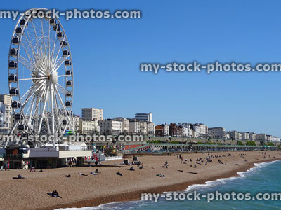 Stock image of big wheel attraction, beach and tourists in Brighton