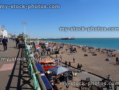 Stock image of Brighton promenade and beach, with tourists, parasol umbrellas