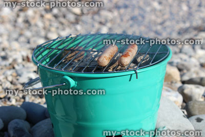 Stock image of sausages being turned on beach charcoal with tongs