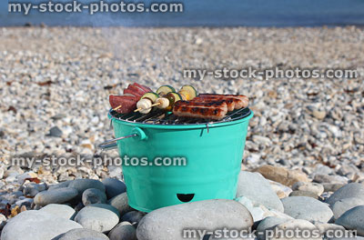 Stock image of bucket shaped charcoal barbecue / BBQ on pebble beach, cooking food