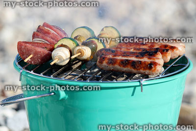 Stock image of smoking charcoal barbecue bucket, vegetable / mushroom kebabs, sausages