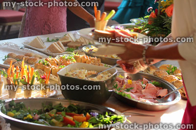 Stock image of people serving themselves, buffet table of party food