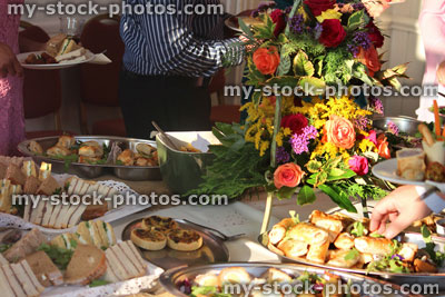 Stock image of people serving themselves, buffet table, party food, flower display