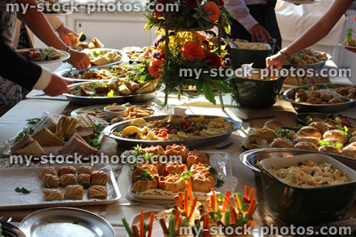 Stock image of people serving themselves, buffet table of party food